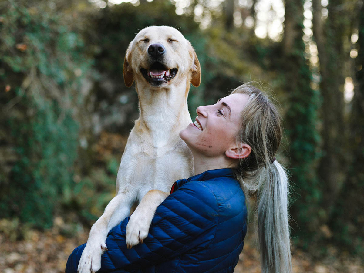 Happy woman carries dog lovingly